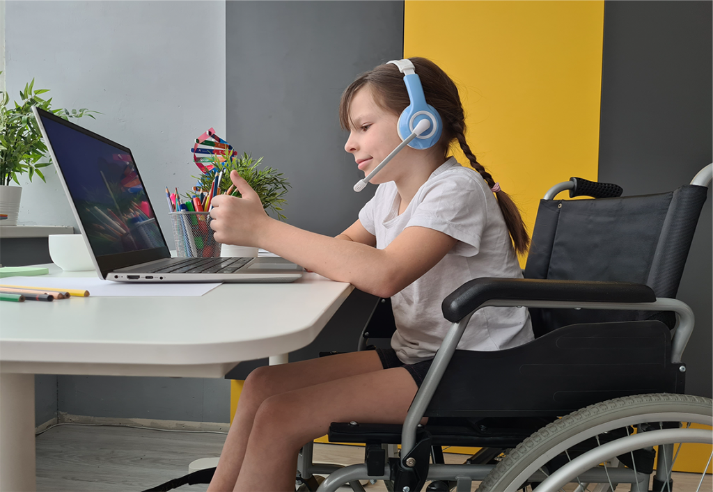 Young girl in a wheelchair with a headset and microphone interacting with other people using a laptop computer